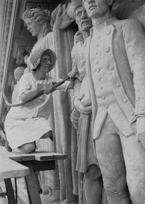 Photograph of Daphne Mayo working on her sculpture on the Brisbane City Hall tympanum in 1930.