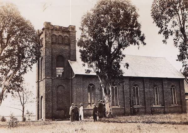 A black and white photograph of St Peter's Church in Campbelltown. A group of people are gathered together in the foreground.