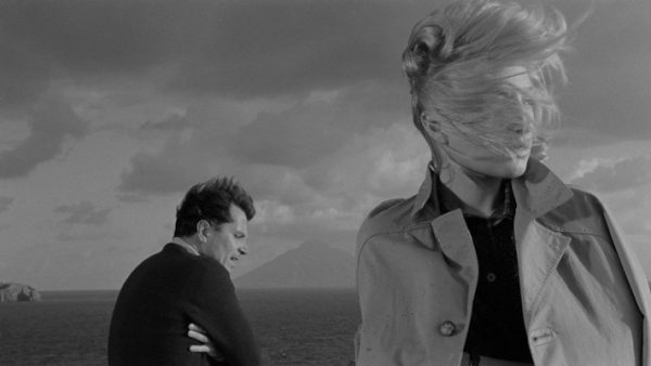 A screenshot from Antonioni's film L'Avventura, which depicts a woman and a man in a windswept scene.