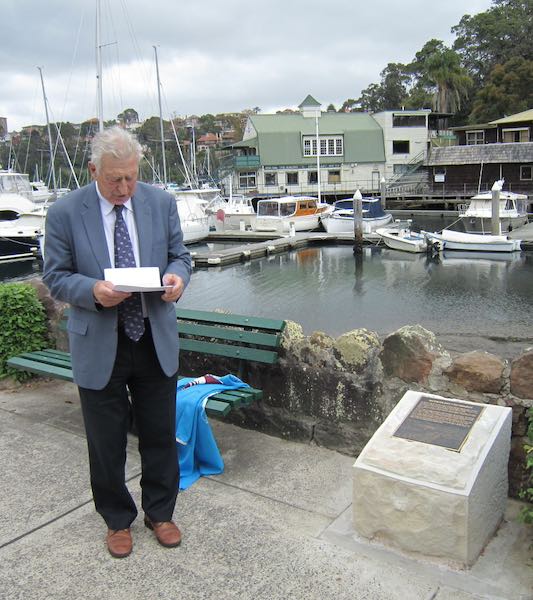 Peter Abelson reads from a sheet of paper at the unveiling of a plaque.