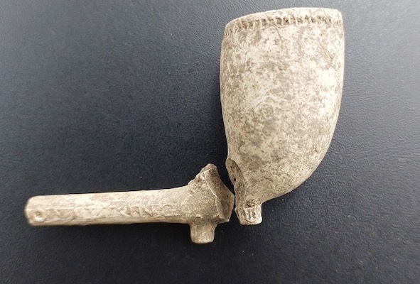 Photograph of a broken clay pipe found at an archaeological site.